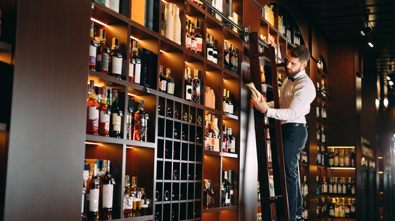 Man holding bottle, liquor shelves