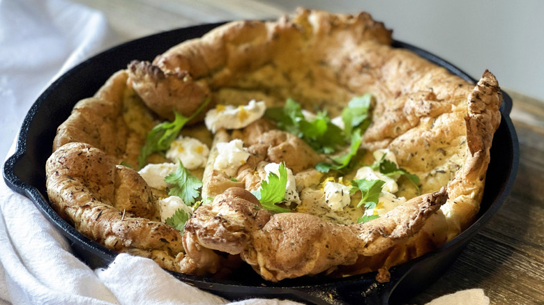 Dutch baby with goat cheese and herbs in skillet