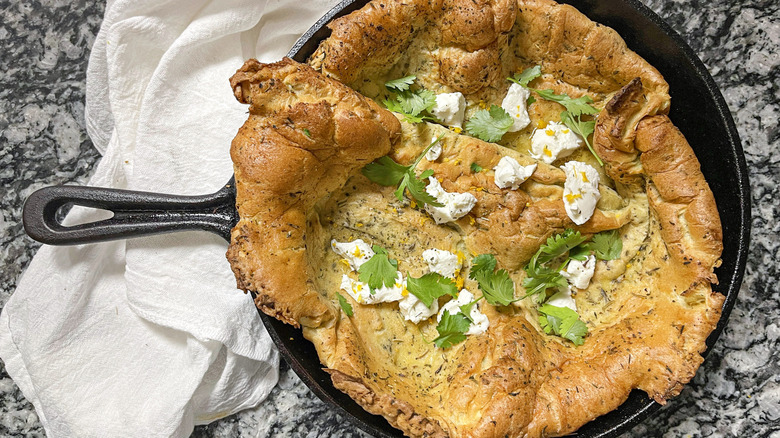 Herb and cheese covered Dutch baby in cast iron skillet