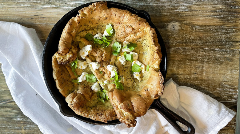 Dutch baby in skillet with goat cheese and herbs