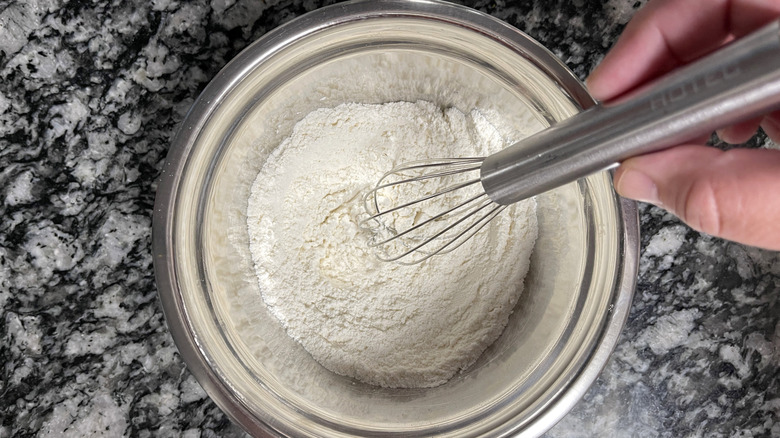 Hand whisking flour in mixing bowl