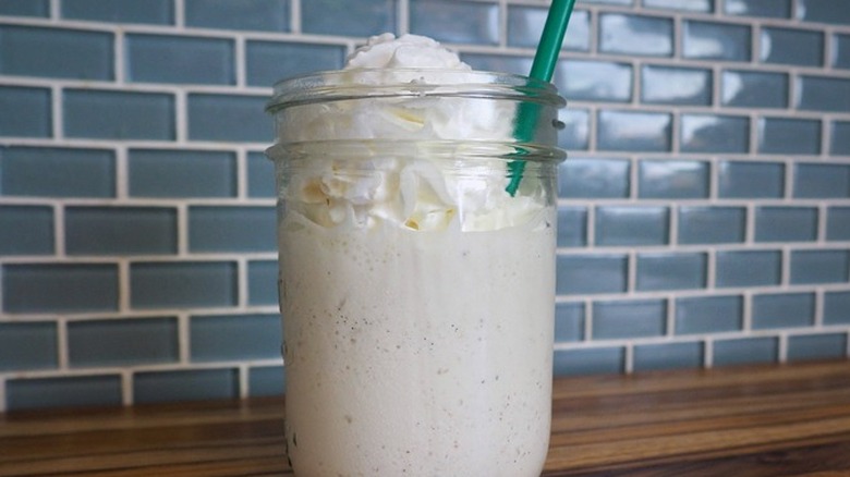 Mason jar with thick vanilla frozen drink and straw.