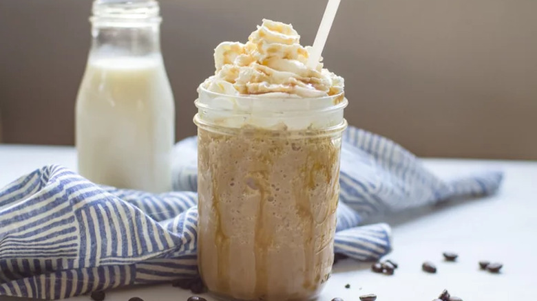 Mason jar with frozen coffee drink and whipped cream. 