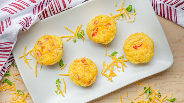 Mini cooked quiches with shredded cheese. 