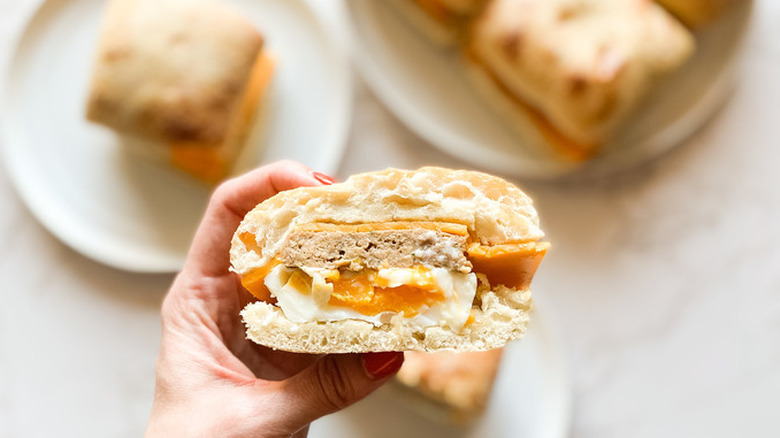 Hand holding breakfast sandwich with egg inside 