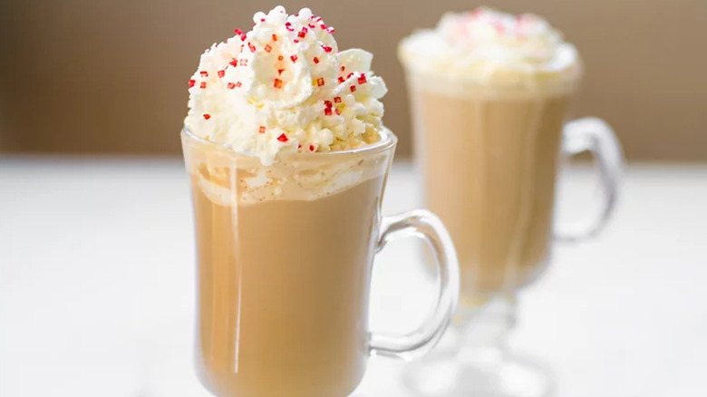 Glass mugs of creamy coffee drinks with whipped cream. 