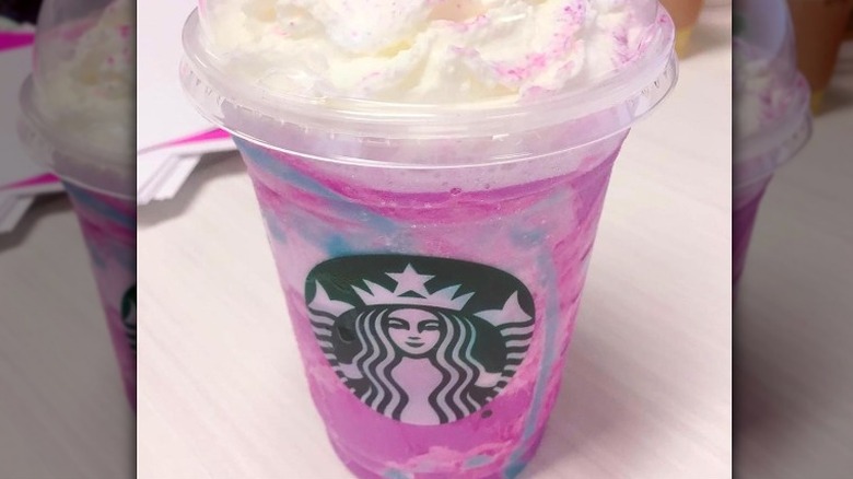 Starbucks cup with pink and blue swirled drink.