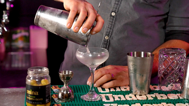 Hand pouring cocktail from shaker