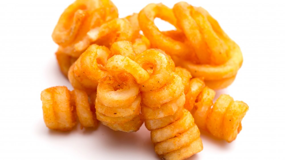 Seasoned curly fries against a white background