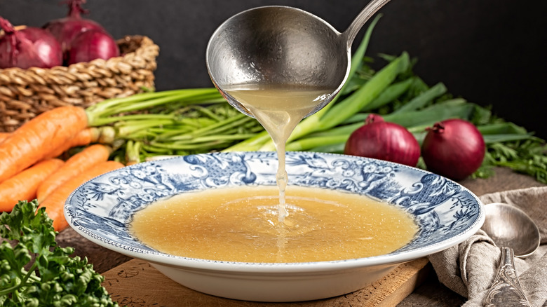 ladeling chicken broth into a bowl