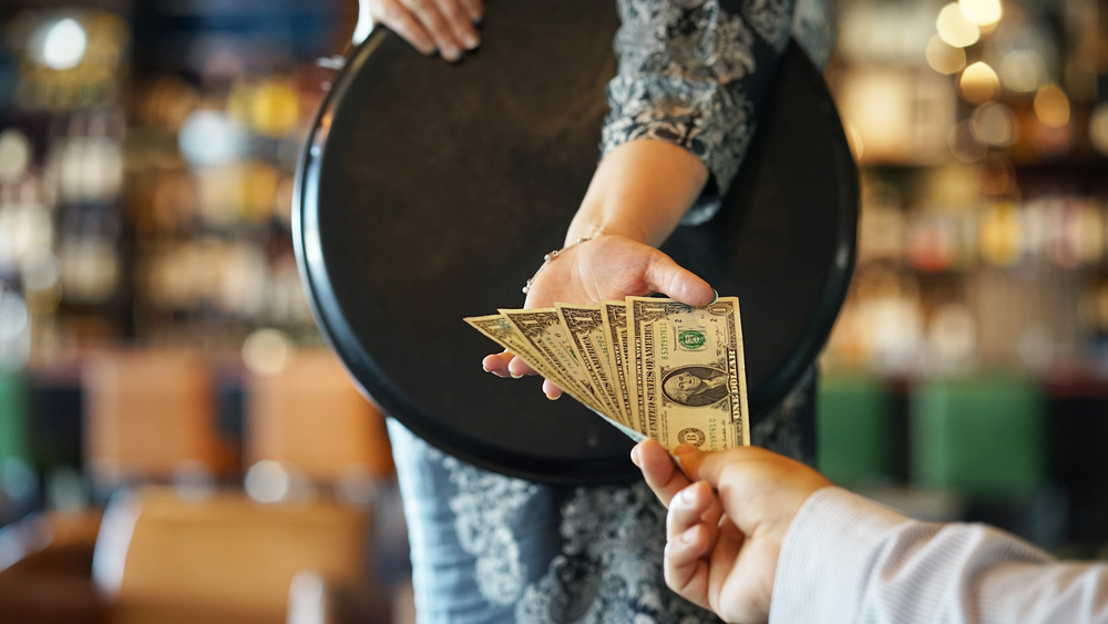 Man hands tip to female server