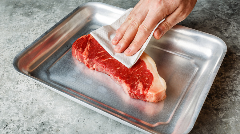 patting steak dry with paper towel