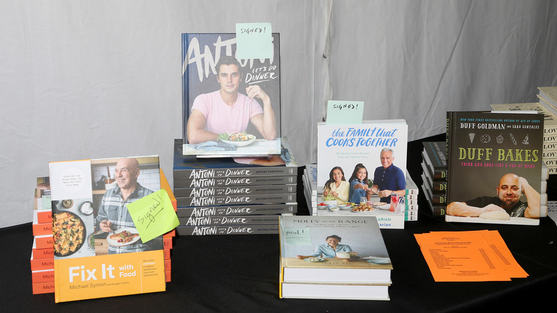 Various celebrity cookbooks piled on top of a table