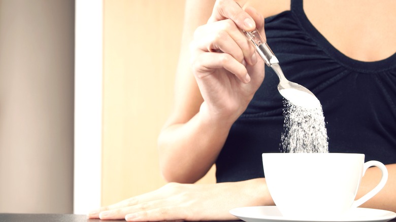 Person spooning sweetener into cup