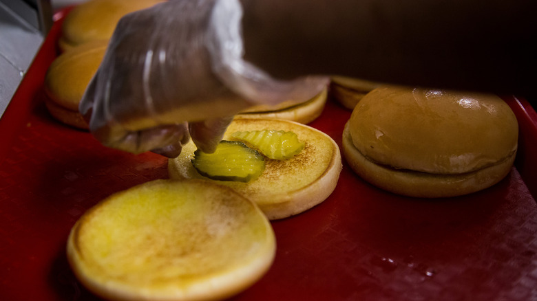 Worker in gloved hands assembling chicken sandwiches