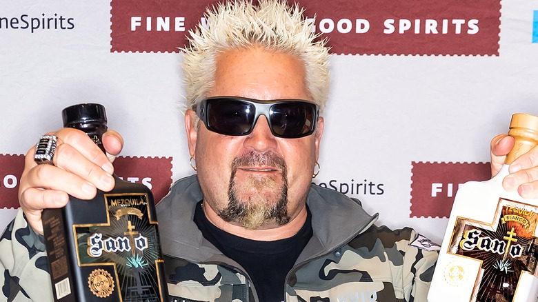 Guy Fieri holding up bottles of Santo tequila