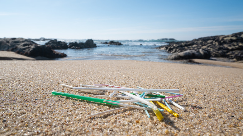 single use plastic bendy straws lying on beach