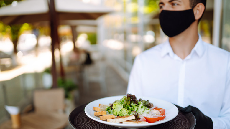 Waiter serving food wearing mask during pandemic