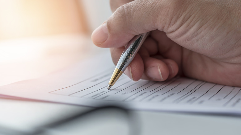 Close-up of hand holding pen and filling out an application