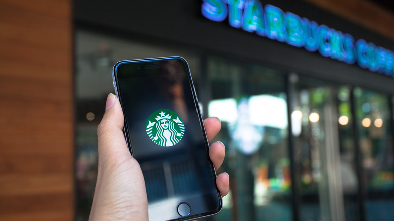 A hand holding a phone with Starbucks' mobile app