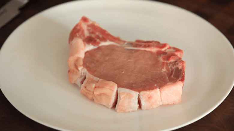 A raw pork chop with properly cut fat