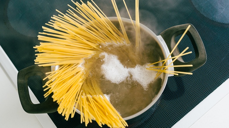 Boiling water with noodles on stove