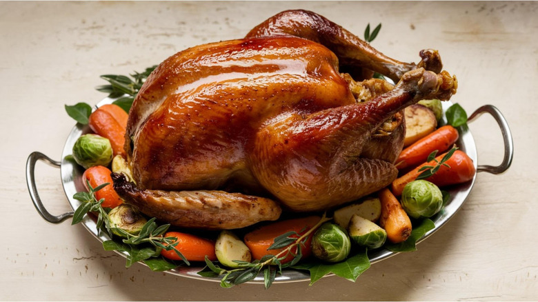 Cooked Thanksgiving turkey with carrots and Brussel sprouts on metal serving tray