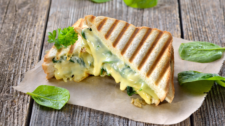 Grilled cheese with spinach setting on a wooden table