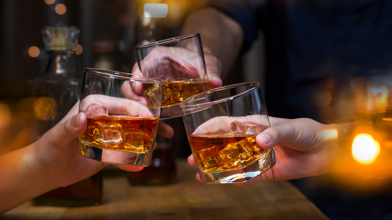 Several people toasting with whiskey glasses