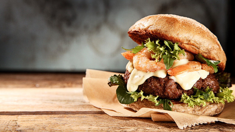 Burger on bun atop brown paper wrapper