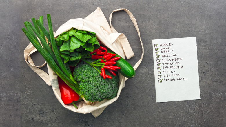 Shopping bag full of vegetables next to completed grocery list