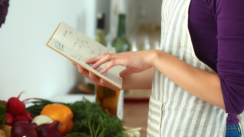 Reading cookbook with food in kitchen