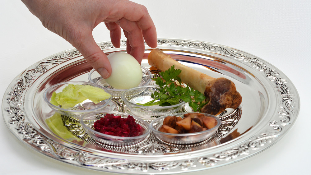 Hand placing egg on Seder plate