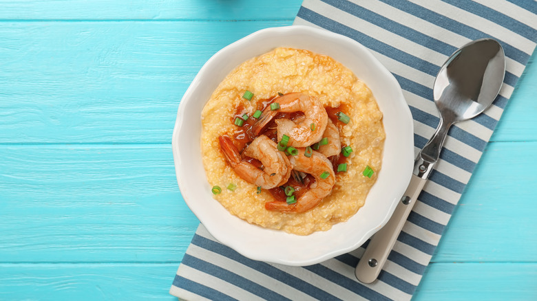 White bowl of shrimp and grits on striped napkin