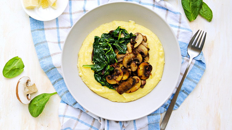 White bowl full of grits, spinach, and mushrooms
