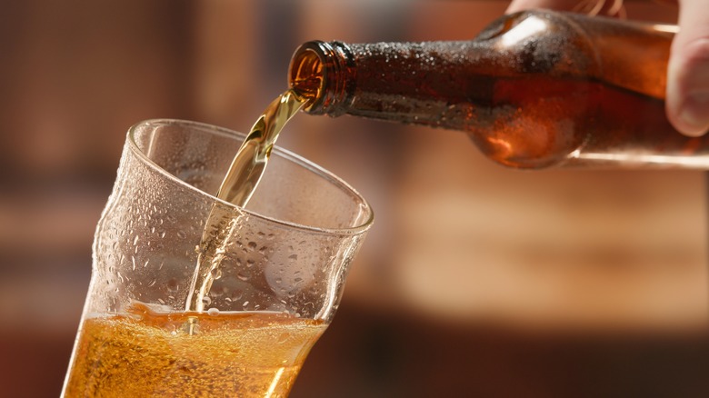 Person pouring bottle of beer into glass