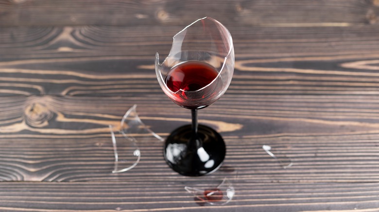 broken wine glass with red wine on wood background