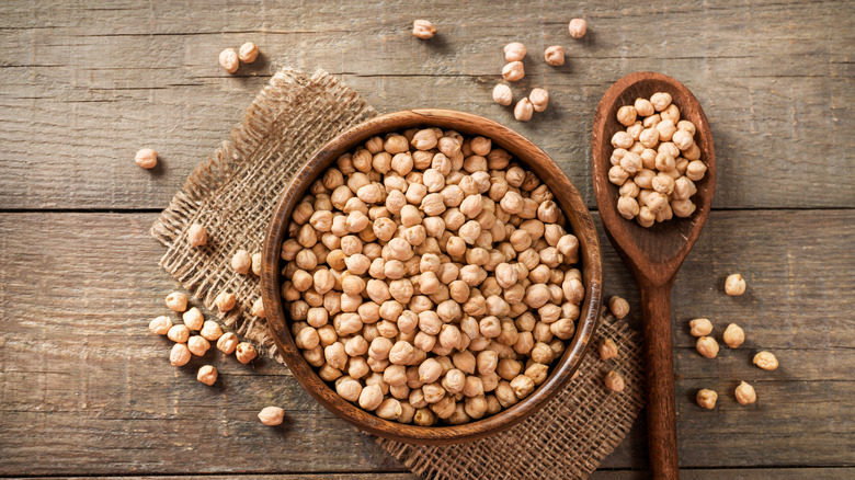 Bowl and spoon of dried chickpeas on wooden table