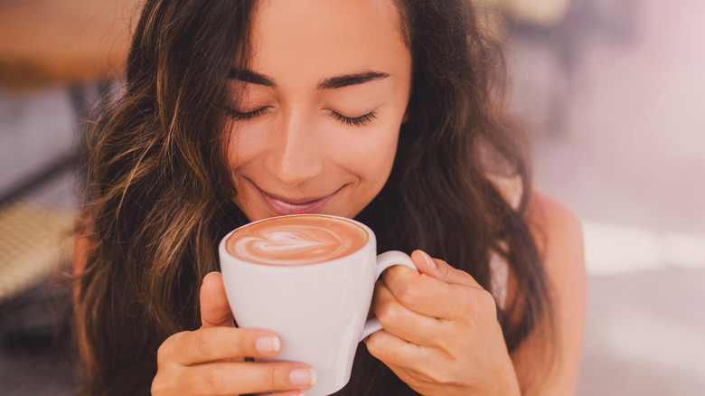 Smiling woman holding cappuccino