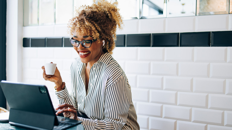 Happy woman working while holding coffee