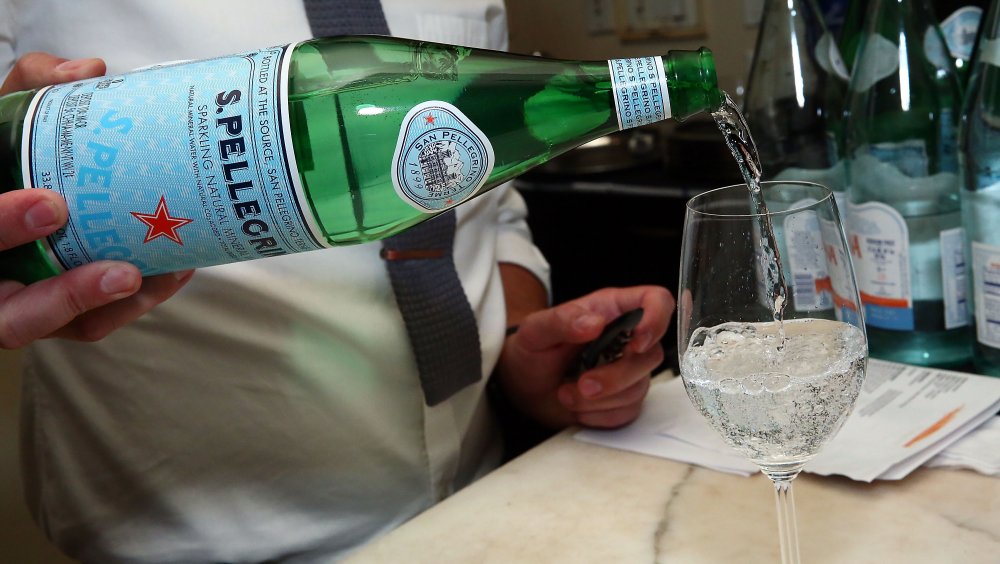 A waiter pours a glass of San Pellegrino 