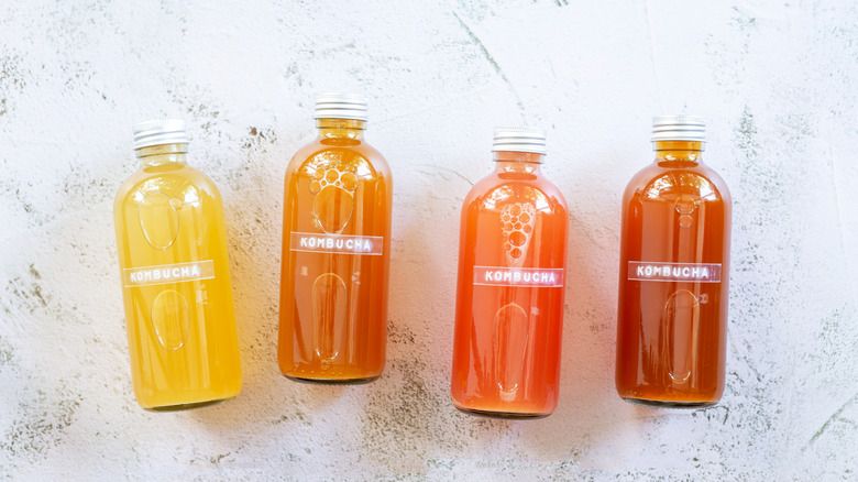 Colorful glass bottles of kombucha on marble table