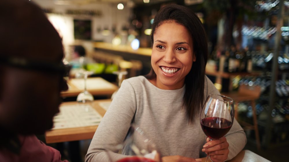 A woman holds a glass of red wine