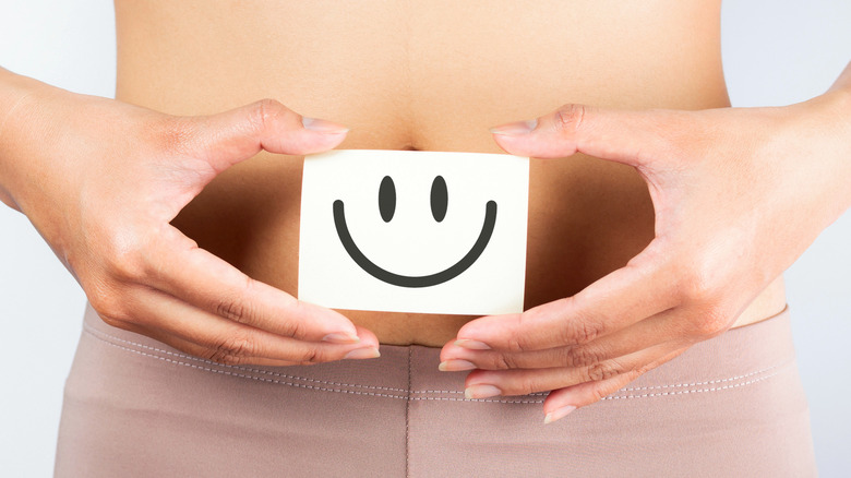 Woman holding smiley face over stomach