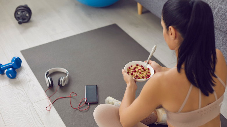 Woman on yoga mat eating oat cereal