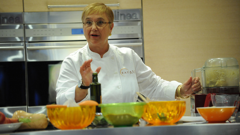 Lidia Bastianich wears a chef's jacket in a kitchen