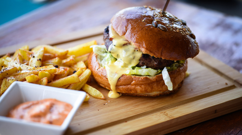 Cheeseburger and fries on wooden board