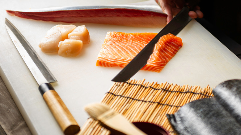 Cutting a piece of fish with knife to the left 