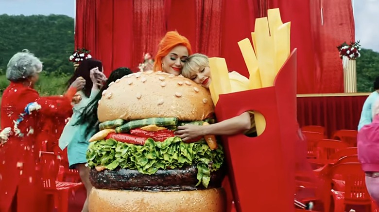 Swift dressed in fry costume hugging a hamburger