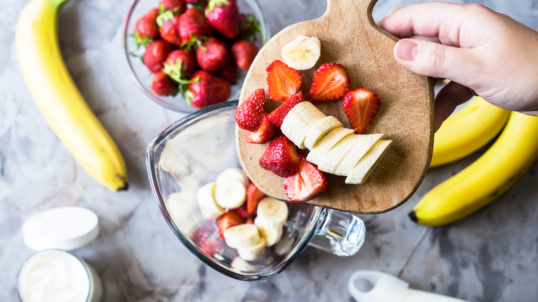 Bananas and strawberries being poured into blender